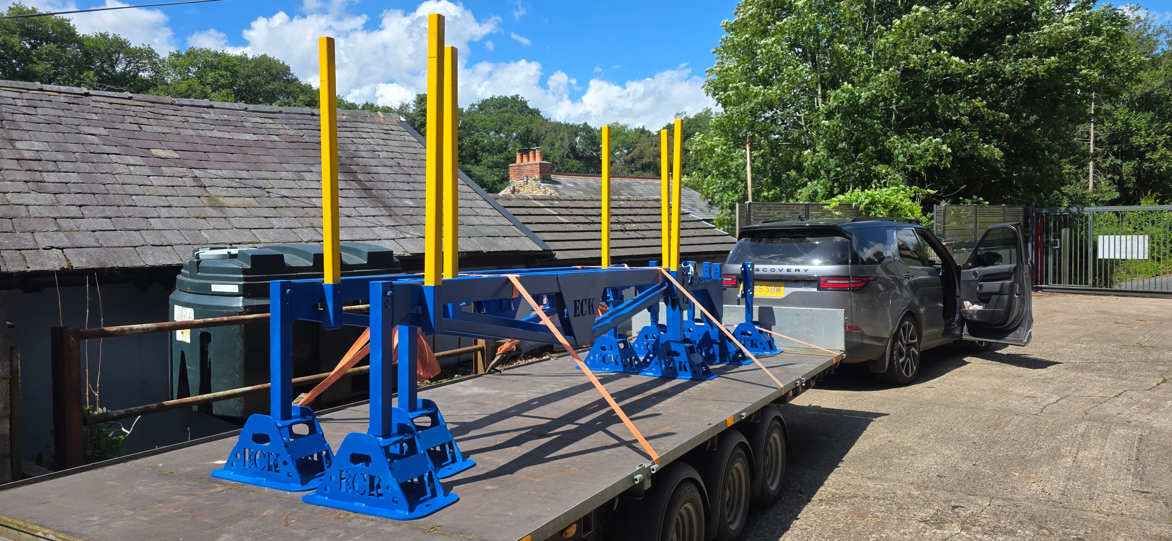 Blue steel framework with yellow posts on flatbed trailer