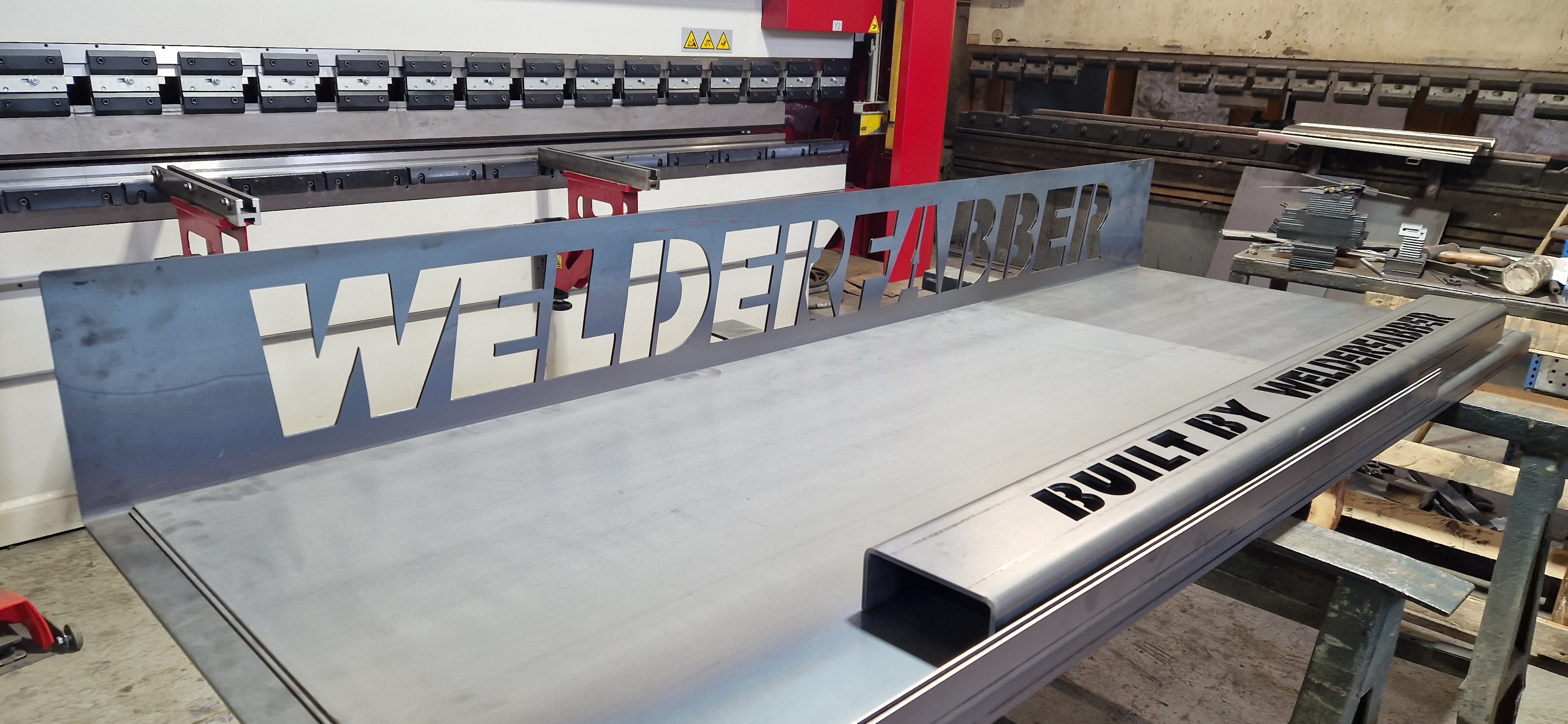Welder Barber laser cut steel sign on press brake