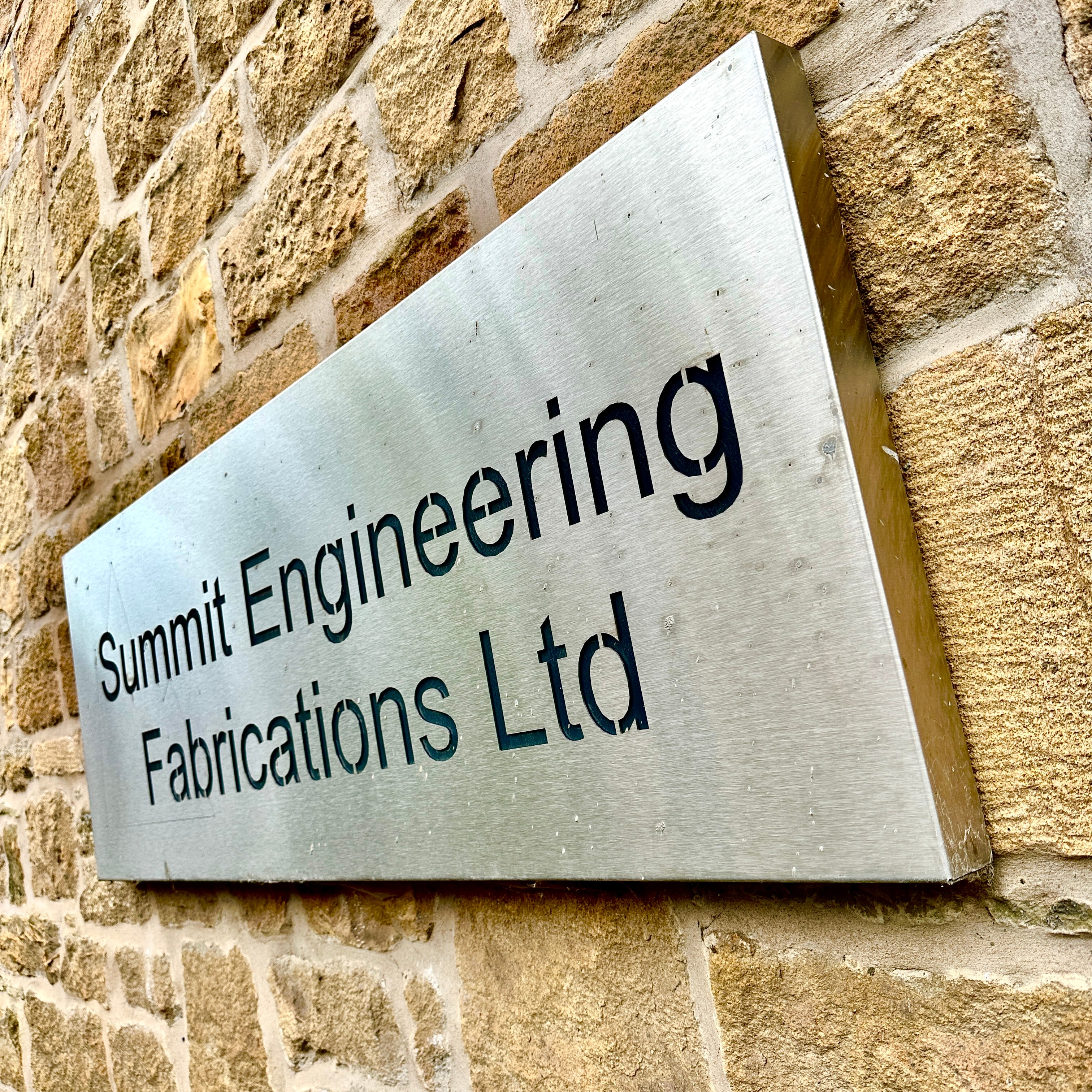 Summit Engineering Fabrications Ltd brushed steel sign on stone wall